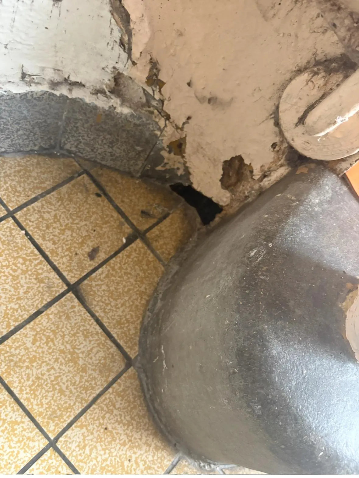Ouverture au pied d’un mur à côté d’un passage de réseau